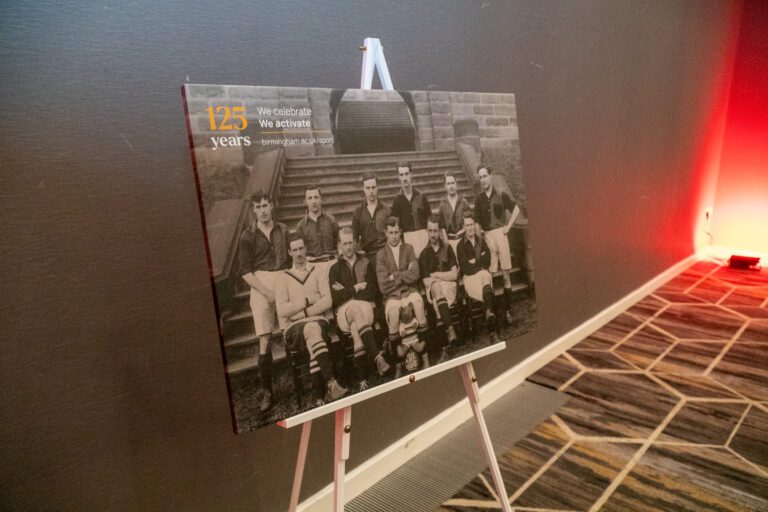 An image of a canvas printed with an old photo of the football team in black and white, balanced on an easel.