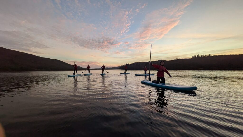 People on a lake participating in stand up paddleboarding