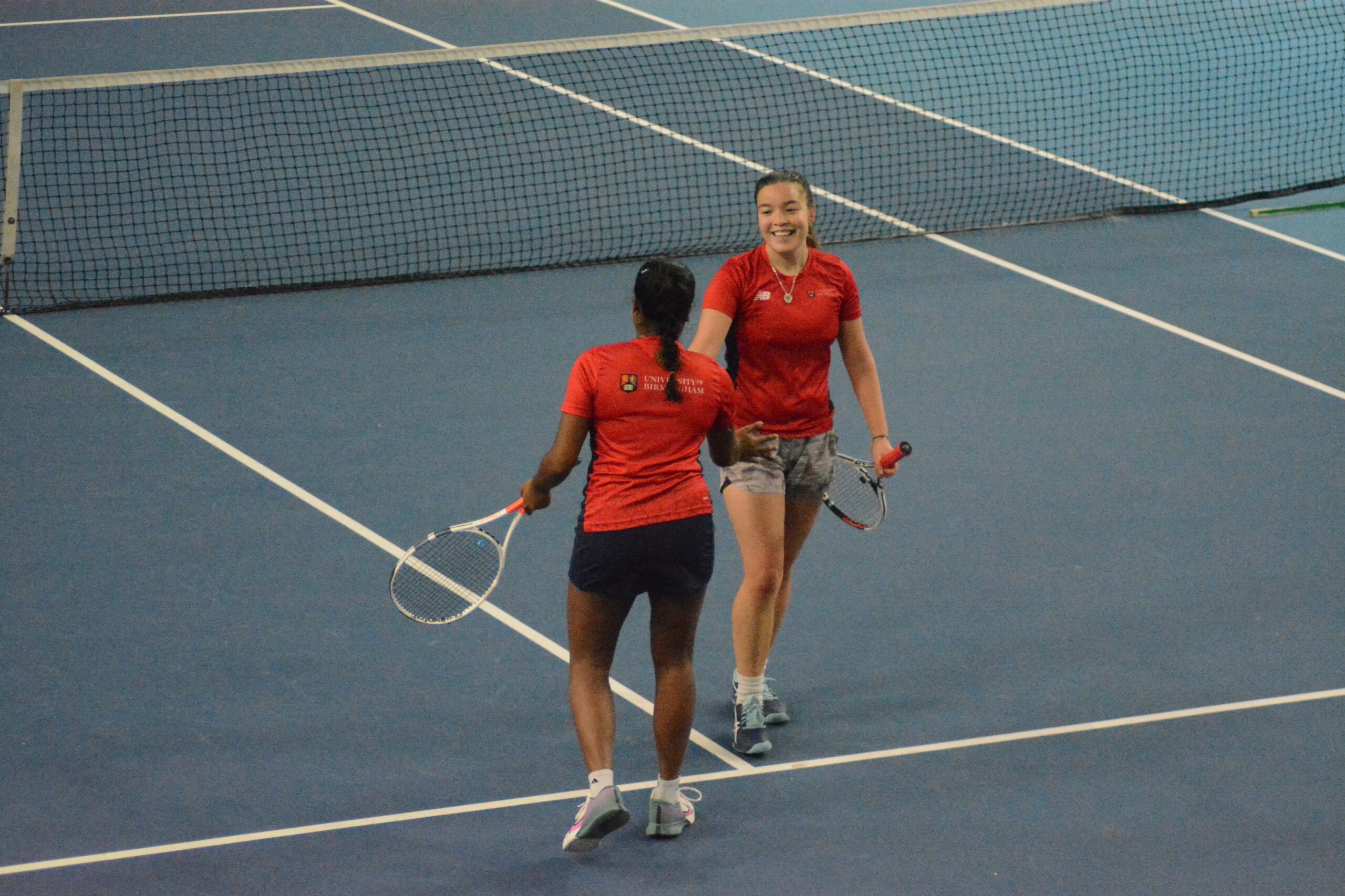 Two tennis players high fiving each other. They are happy