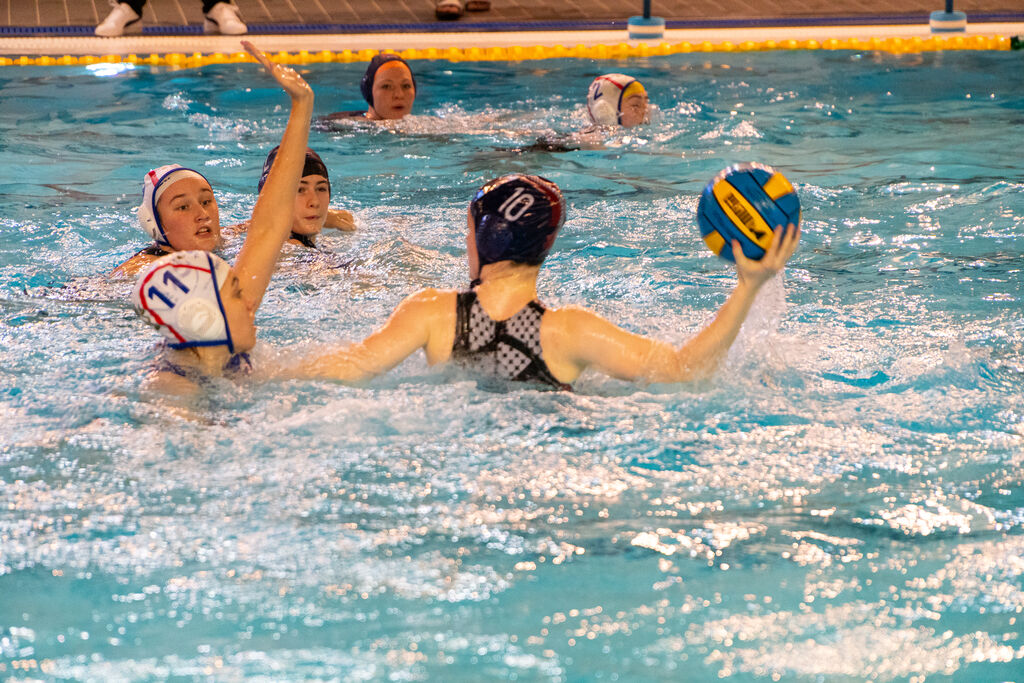 Women's water polo in action, with a University of Birmingham student defending the ball in the pool.