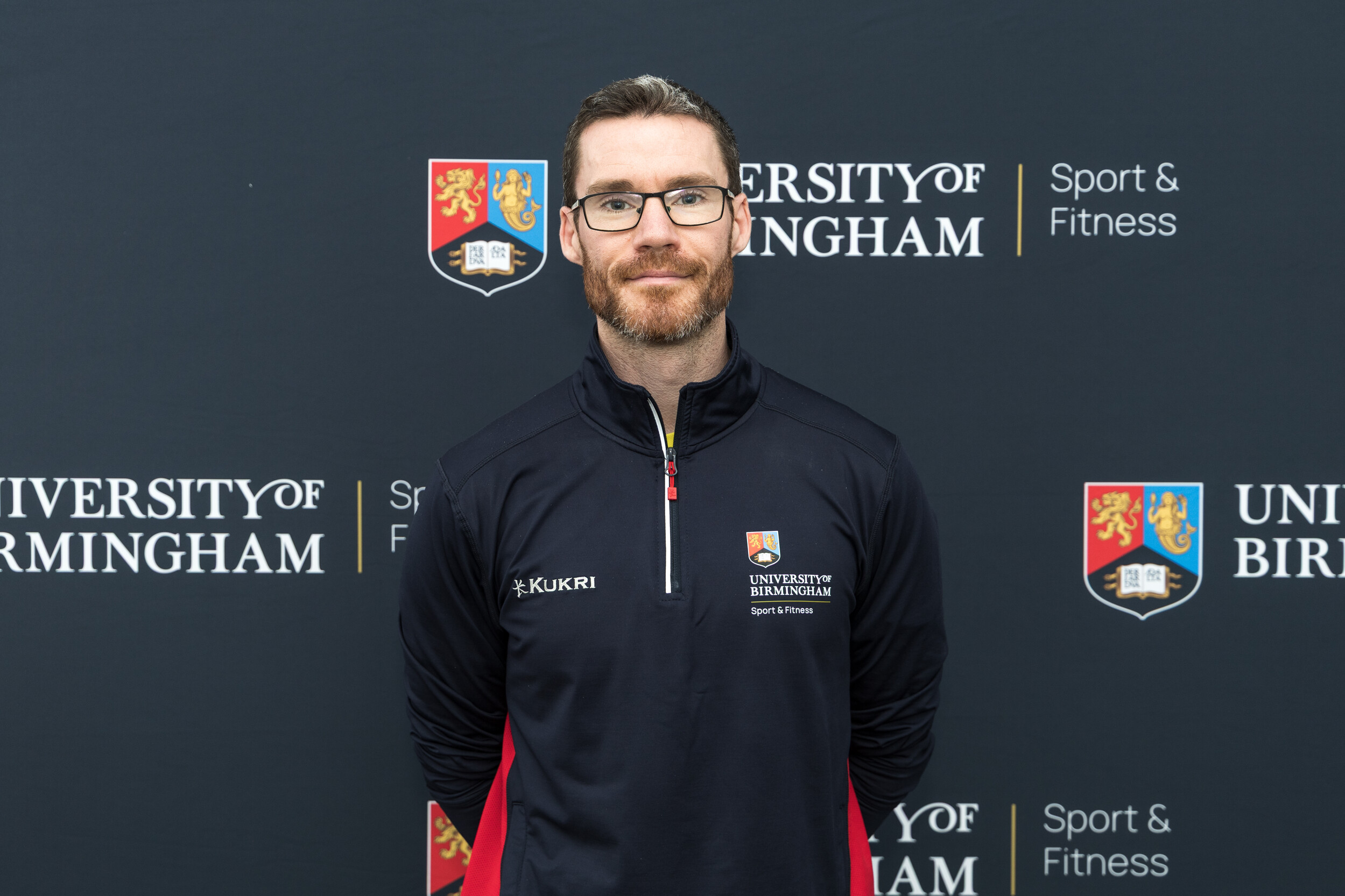 Man smiling in front of backdrop
