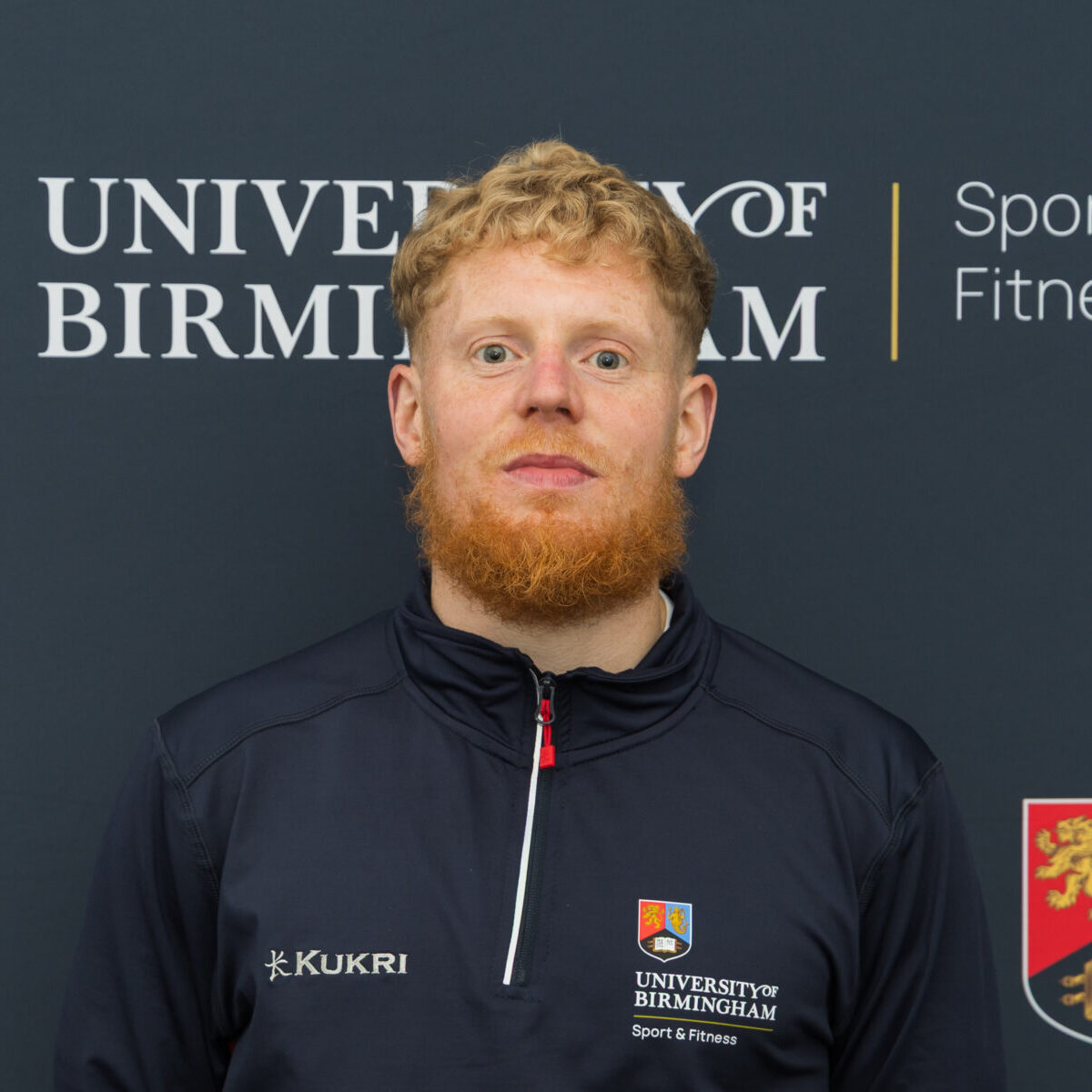 Man smiling in front of backdrop.