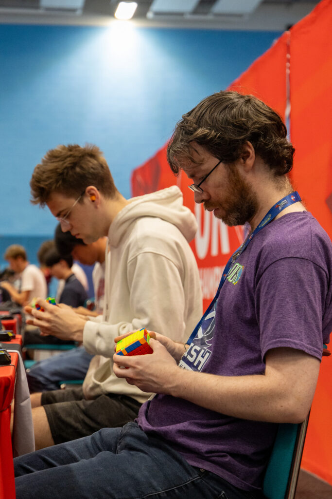 Men in a line working on their Rubik's Cubes.